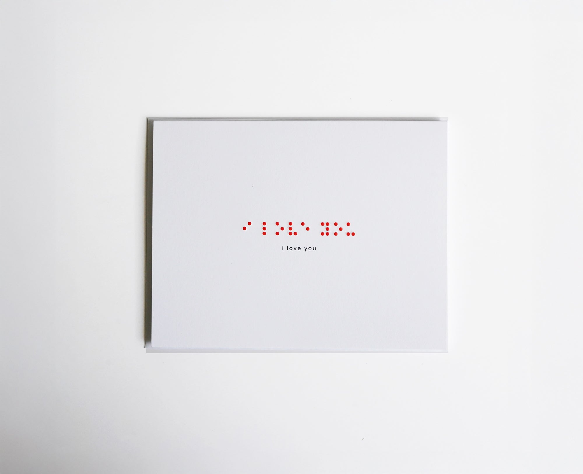Red greeting card with "I LOVE YOU" in embossed Braille, handmade and tactile, paired with a white envelope.