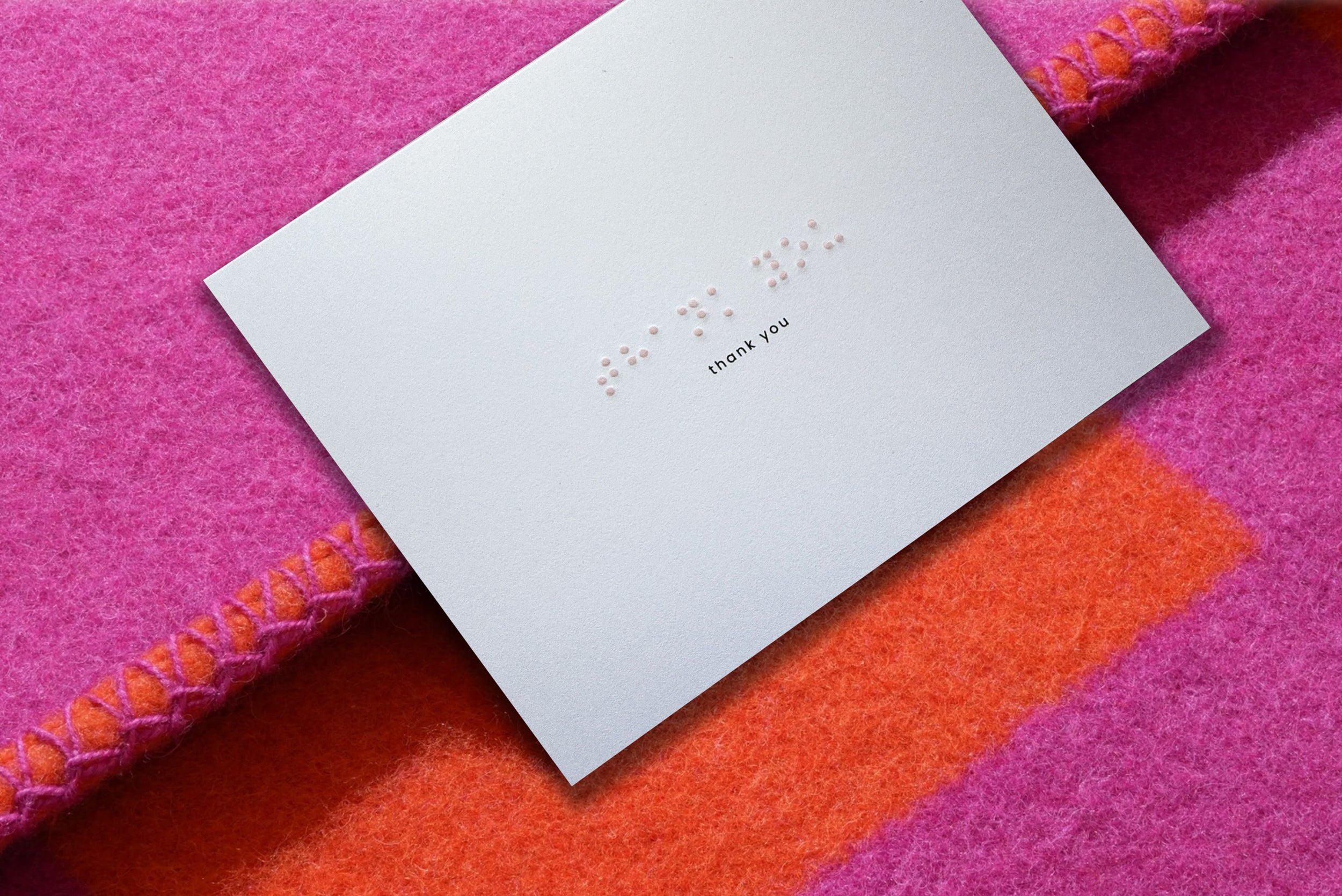 braille thank you card on top of some pink sheets